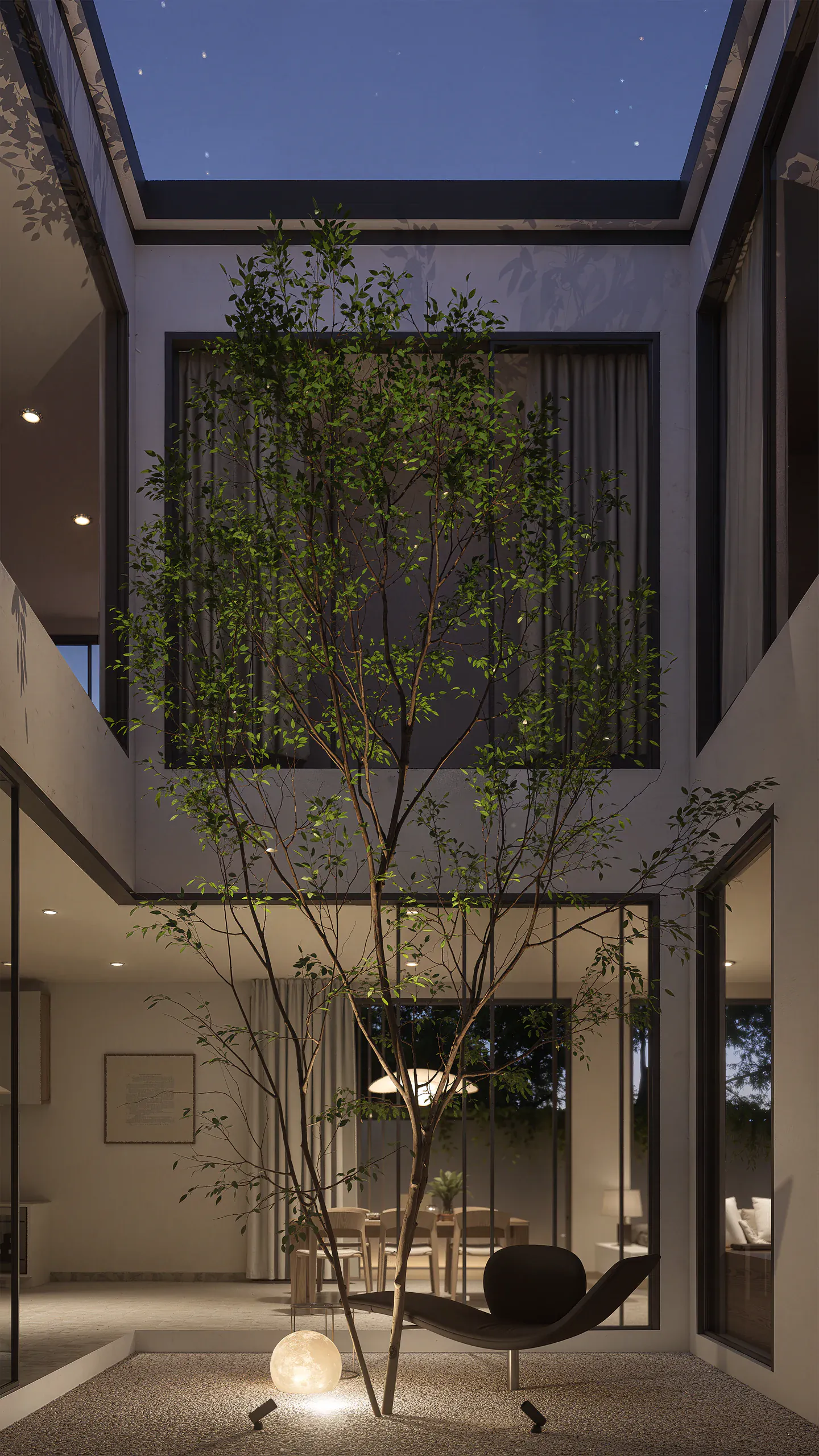 Vertical evening view of the courtyard illuminated from within and framed by upper-floor circulation.